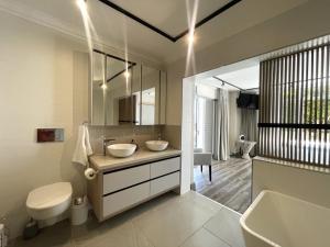 a bathroom with two sinks and a toilet and a tub at Aquarella 2 in Plettenberg Bay