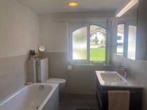 a bathroom with a tub and a toilet and a sink at Apartment Margherita in Sedrun