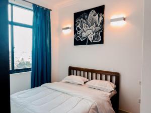 1 dormitorio con 1 cama con cortinas azules y ventana en Elles Residence, en Dar es Salaam