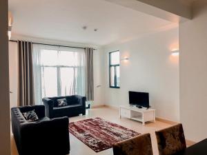 a living room with a couch and a tv at Elles Residence in Dar es Salaam