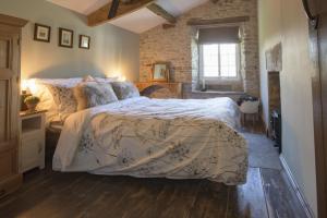 a bedroom with a bed and a brick wall at Pond Cottage in West Witton