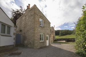 an external view of a stone house with a driveway at Pond Cottage in West Witton