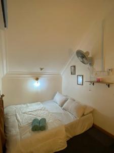 um quarto com uma cama com dois sapatos verdes em Abe.Cottage 3 em Kampong Chawat
