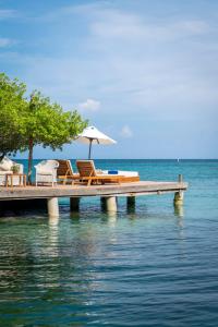 a dock with chairs and an umbrella on the water at Hotel Coralina Island in Isla Grande