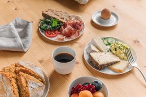 einen Tisch mit Tellern und einer Tasse Kaffee in der Unterkunft Blyb Hotel in Gmund am Tegernsee