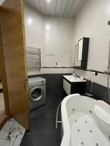 a bathroom with a tub and a sink and a washing machine at City Center Apartment in Kutaisi