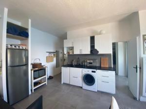 een keuken met witte kasten en een wasmachine en droger bij Cassis Appartement bord de mer, vue exceptionnelle in Cassis