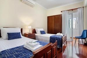 a bedroom with two beds and a blue chair at Central Living Funchal in Funchal
