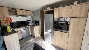 une cuisine avec des placards en bois et des appareils en acier inoxydable dans l'établissement Mobil home 3 chambres 40 m2, à Quiberon