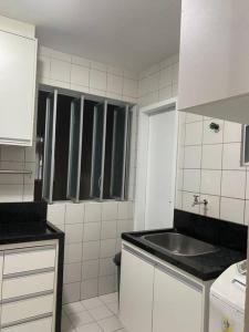 a white kitchen with a sink and a counter top at Lindo apartamento in Aracaju