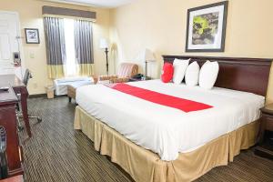 Cette chambre comprend un grand lit avec des oreillers rouges et blancs. dans l'établissement Bonita Lakes Inn by Capital O Meridian I20, à Meridian