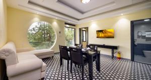 a living room with a white couch and a dining room table at Four Spring Villas & Golfs Da Lat in Da Lat