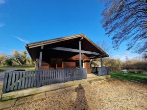 a small wooden cabin with a porch and a fence at Kingfisher Lodge-HuntersMoon -Warminster-Longleat-Bath in Warminster