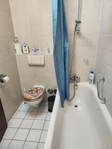 a bathroom with a toilet and a tub with an umbrella at Ferienwohnung Lay in Hirschaid