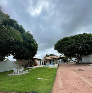 ein Haus mit einem Tisch und Stühlen im Gras in der Unterkunft Pousada MKC in São Gonçalo do Amarante