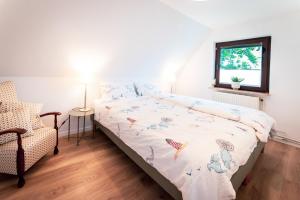 ein Schlafzimmer mit einem Bett und einem Stuhl und einem Fenster in der Unterkunft Ferienhaus Meergefühl in Neukirchen