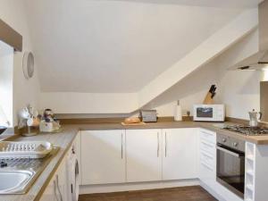 a white kitchen with white cabinets and a sink at The Rafters, Bank House, Stunning Apartment. in Millom