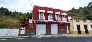 um edifício vermelho com duas portas de garagem numa rua em Casa Los Guanches em La Guancha