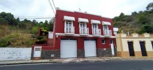 a red building with two garage doors on a street at Casa Los Guanches in La Guancha