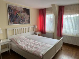 a bedroom with a white bed with red curtains at Hotel zum Grafen Hallermunt in Springe