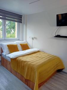 a bedroom with a bed with a yellow blanket on it at Apartament Gliwice Mewy in Gliwice