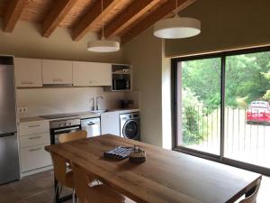 a kitchen with a wooden table and a large window at Cal Mureu in Pardines