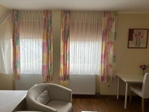 a bedroom with curtains and a chair and a table at Hotel zum Grafen Hallermunt in Springe