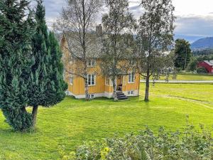 una gran casa amarilla en un campo con árboles en 6 person holiday home in AVERØY-By Traum, en Stein