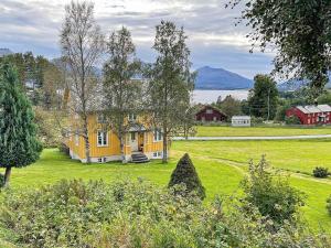 ein gelbes Haus auf einem grünen Feld mit Bergen im Hintergrund in der Unterkunft Holiday home AVERØY VI in Stein