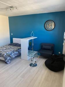 una camera da letto con una parete blu, un letto e una sedia di Appartement tout confort a Limoges