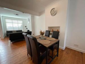 a dining room with a table and chairs and a clock at A lovely Three bedroom house in Windsor in Windsor