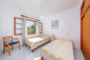 sypialnia z 2 łóżkami, krzesłem i oknem w obiekcie Casa Juan w mieście Colonia de Sant Pere