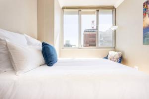 ein weißes Bett mit weißen Kissen und einem Fenster in der Unterkunft Perspectives on Roeland in Kapstadt