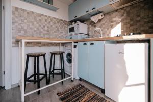 uma cozinha com máquina de lavar e secar roupa e 2 bancos de bar em Spacious studio near lake em Năvodari