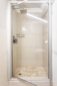 La salle de bains est pourvue d'une douche avec une porte en verre. dans l'établissement Perspectives on Roeland, au Cap