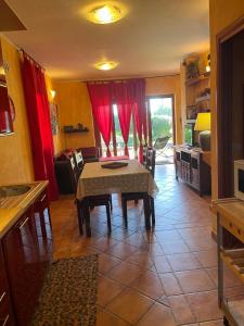 a kitchen with a table and red curtains at La Casa sulla collina "Baccu e Idda" in Chia