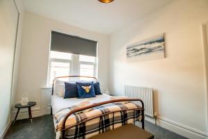 a bedroom with a bed with blue pillows and a window at Lovely 3BR Flat in the Heart of South Shields in South Shields