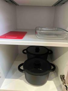 a kitchen shelf with a black pot and a lid at Studio proche de l’aéroport/gare/centre ville in Charleroi