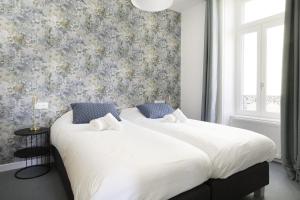 2 camas en un dormitorio con papel pintado con motivos florales en Villa Pax 3 - La Bourboule - 6pers, en La Bourboule