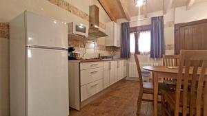 eine Küche mit einem weißen Kühlschrank und einem Tisch in der Unterkunft El Mirador de la LLeira in Ferreras de Arriba
