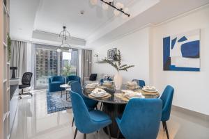 a dining room with a table and blue chairs at Vogue Downtown - Opera Grand - Burj Khalifa & Fountain Views in Dubai