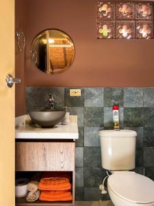 a bathroom with a toilet and a sink and a mirror at Cabin Retreat: Private Studio in Medellín