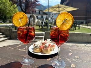 three wine glasses sitting on a table with a plate of food at Hotel Diana in Auronzo di Cadore