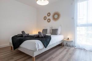 a white bedroom with a bed with a black blanket at La Belle Vue - Garage Terrasse Wi-Fi Netflix Disney+ in Annecy