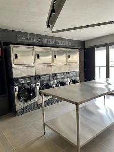 a laundry room with three washing machines and a table at Studio Oscar Freire, linda vista de SP!1716 in Sao Paulo