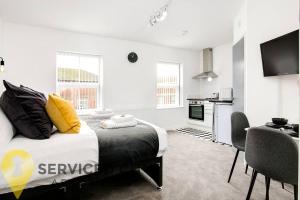 a bedroom with a bed with yellow pillows and a kitchen at SCA - Delightful Studio - VS3 in Wolverhampton