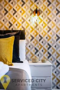 a bedroom with a bed and a yellow and grey patterned wall at SCA - Delightful Studio - VS3 in Wolverhampton