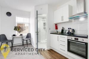 a kitchen with white cabinets and a table with chairs at SCA - Fantastic Studio - VS4 in Wolverhampton