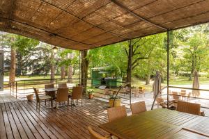 a wooden deck with tables and chairs and trees at L'HORTE in Revel