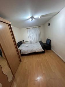 a bedroom with a bed and a room with a wooden floor at Cozy 1 bedroom apartments in East London in London